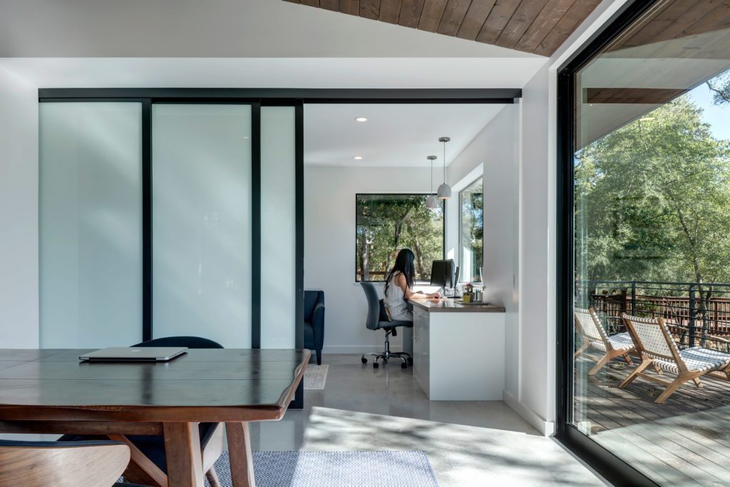 Frosted glass wall sliding door divides  home office area and dinning room 