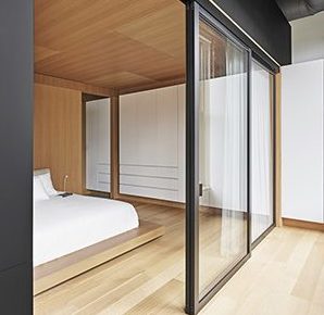 Clear glass sliding door splits bedroom and hallway