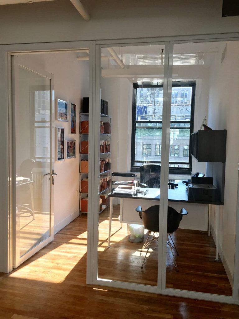 Home office space divided by two clear glass panels with glass swing door 