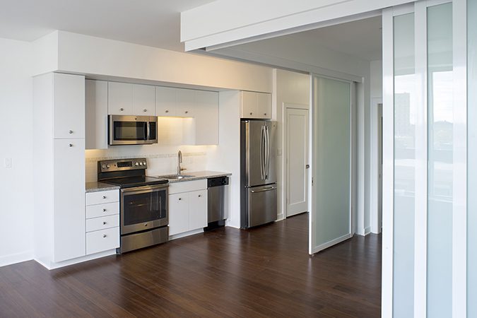 L shape suspended door with white frames separates kitchen from the living room area