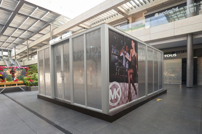 Frosted glass sliding door kiosk with Michael Kors poster