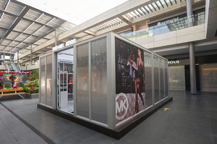 Frosted glass kiosk boutique with Michael Kors poster