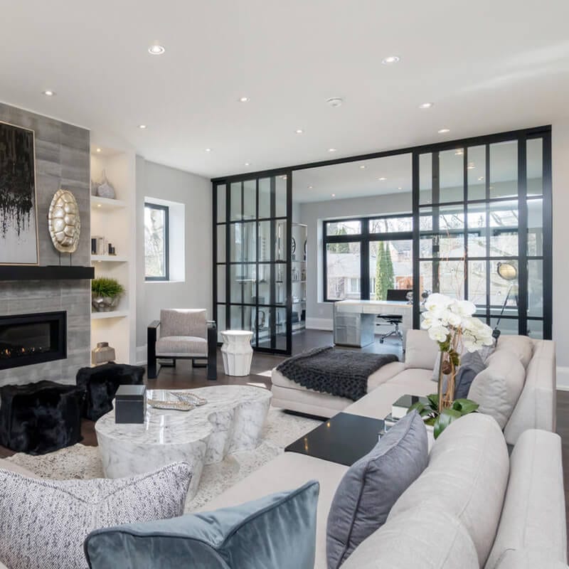 Cozy living room and home office divided by metal frame clear glass sliding doors