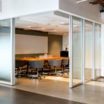 Wooden table with chairs in conference room with L shaped silver film sliding doors
