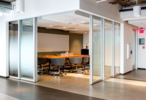Wooden table with chairs in conference room with L shaped silver film sliding doors