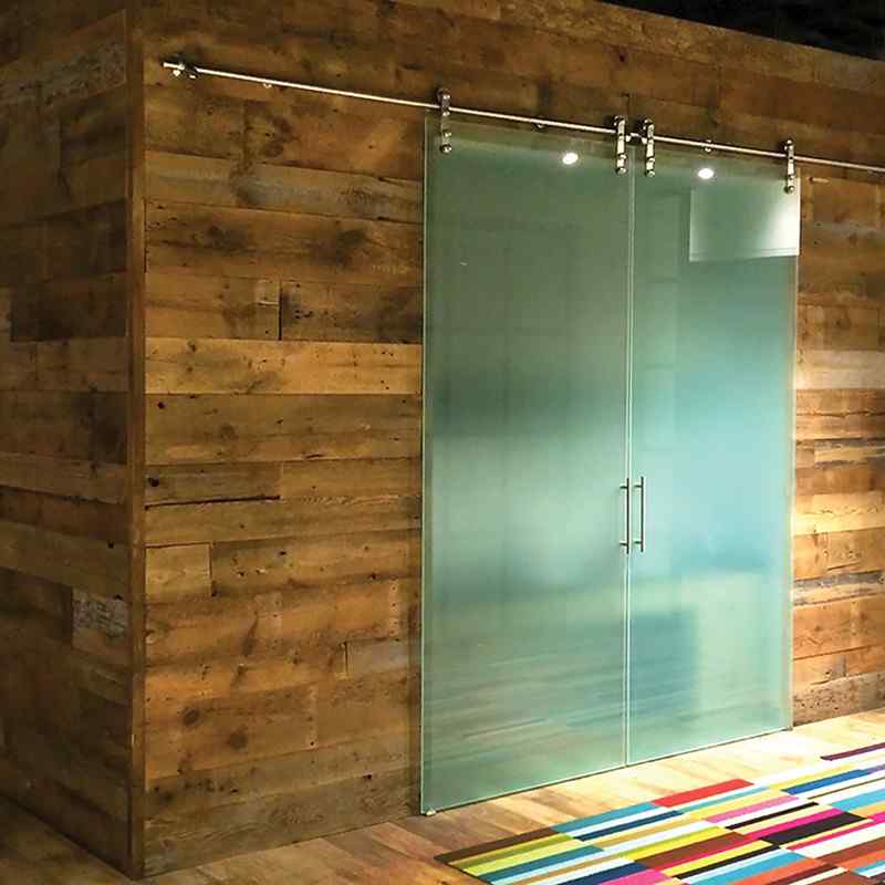 frameless glass barn door with wood wall and rainbow carpet